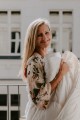 Uśmiechnięta blondynka stoi na balkonie otulona kołdrą wełnianą z wełny merynosów, kołdra AMZ Merino.jpg